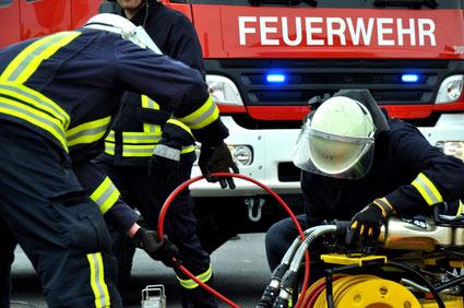 Feuerwehrleute mit Rettungsgerät vor Einsatzfahrzeug